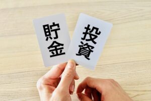 貯蓄と投資のカードを持って考える人のイメージ