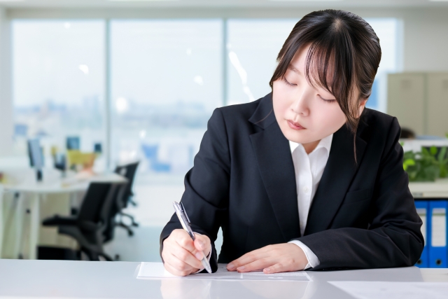 将来を考えながらノートに書く会社員のイメージ